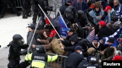 FILE - Pro-Trump protesters tear down a barricade as they clash with Capitol Police during a rally to contest the certification of the 2020 U.S. presidential election results by the U.S. Congress, at the U.S. Capitol Building in Washington, Jan. 6, 2021.