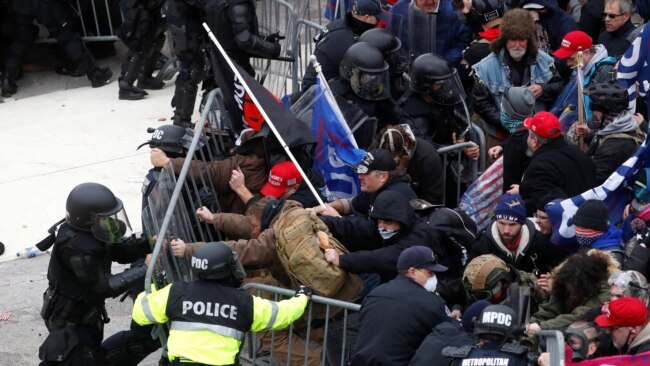 FILE - Pro-Trump protesters tear down a barricade as they clash with Capitol Police during a rally to contest the certification of the 2020 U.S. presidential election results by the U.S. Congress, at the U.S. Capitol Building in Washington, Jan. 6, 2021.