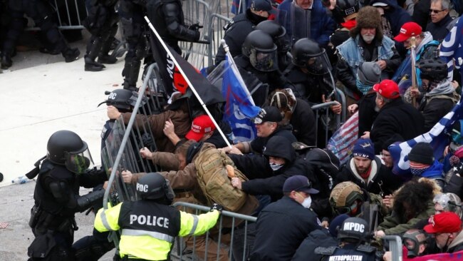 FILE - Pro-Trump protesters tear down a barricade as they clash with Capitol Police during a rally to contest the certification of the 2020 U.S. presidential election results by the U.S. Congress, at the U.S. Capitol Building in Washington, Jan. 6, 2021.