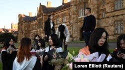 Shiyu Bao (tengah) dan teman-teman sekelasnya yang merupakan mahasiswa internasional dari China, bersiap-siap untuk berfoto dengan gaun kelulusan mereka di sekitar kampus University of Sydney di Sydney, Australia, 4 Juli 2020. (Foto: REUTERS/Loren Elliott