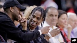 FILE - Rap artist Travis Scott, center, reacts during an NBA basketball game between the Houston Rockets and Denver Nuggets in Houston, April 5, 2017.
