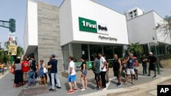 FILE - People wait in line to withdraw cash at a bank in the aftermath of Hurricane Maria, in San Juan, Puerto Rico, Sept. 27, 2017. Maria threw Puerto Rico’s already messy economic recovery plans into disarray. 