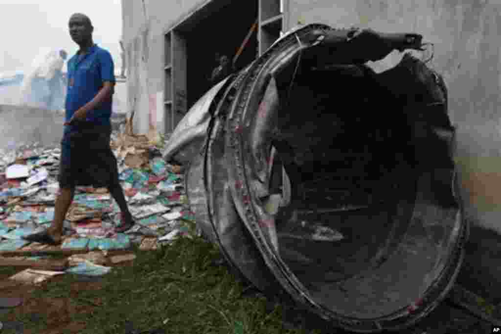 Onlookers walks past what appears to be part of a jet engine assembly of a crashed dana Airlines passenger plane in a neighborhood just north of Murtala Muhammed International Airport, in Lagos, Nigeria, Sunday, June 3, 2012. 