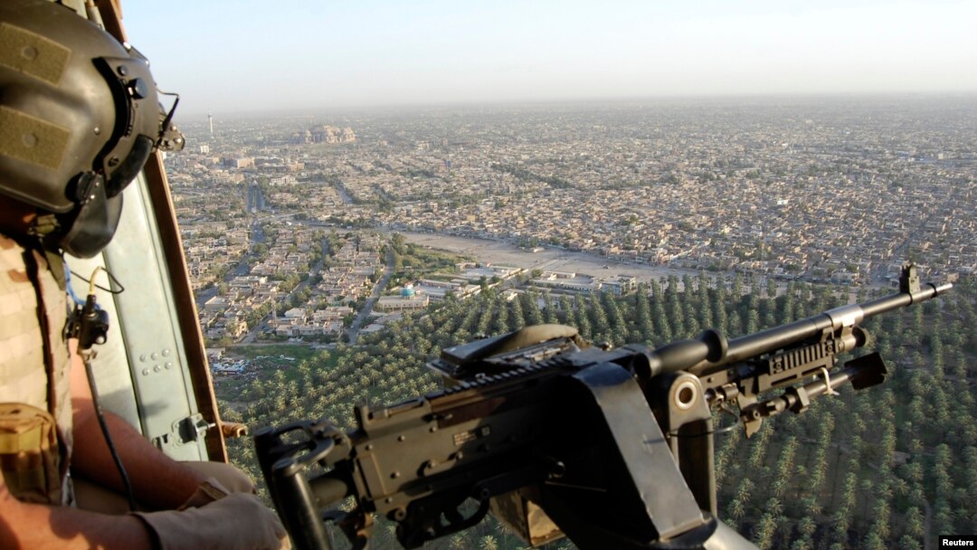 Anggota Angkatan Laut Irak memandang keluar dari helikopter militer di atas kota Baghdad. 