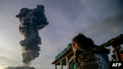 Warga di desa Duono, Maluku Utara, tampak mengamati abu vulkanik yang muncul dalam erupsi Gunung Ibu, pada 15 Januari 2025. (Foto: AFP/Azzam)