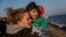 A volunteer holds a baby after her family's arrival on a dinghy from the Turkish coast to the northeastern Greek island of Lesbos on Nov. 17, 2015.
