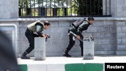 FILE - Members of Iranian forces take cover during an attack on the Iranian parliament in central Tehran, Iran, June 7, 2017. 