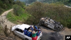 ARCHIVO: Miembros de la Guardia Indígena pasan junto a un vehículo que quemaron después de un ataque de rebeldes del Estado Mayor Central (EMC), en Toribio, Colombia, el martes 19 de marzo de 2024. 