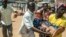 Men carry a woman who passed out as heavy gunfire was directed towards the Baya Dombia school where voters had gathered to cast ballots in a constitutional referendum, in Bangui, CAR, Dec. 13, 2015.
