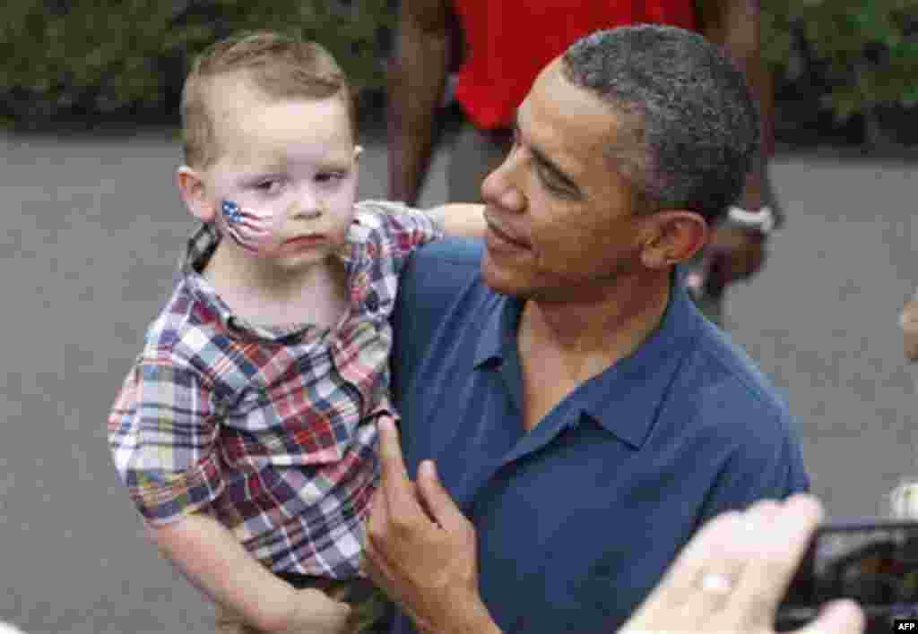 President Barack Obama picks up a child as he greets military families at an Independence Day celebration on the South Lawn of the White House in Washington, Monday, July 4, 2011. (AP Photo/Charles Dharapak)