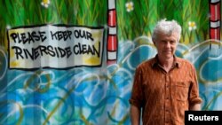 Activist, environmentalist and community leader Peter Macfadyen stands next to a painted storage unit on the banks of the River Frome, in Frome, Britain, June 25, 2019. Picture taken June 25, 2019. REUTERS/Toby Melvill