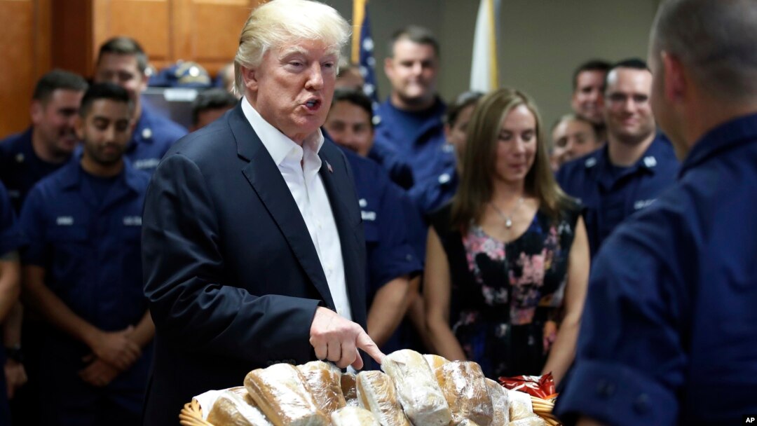 Presiden AS Donald Trump bersiap membagikan sandwich kepada pasukan penjaga pantai AS di Riviera Beach, Florida pada hari Thanksgiving, Kamis (23/11). 