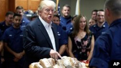 Presiden AS Donald Trump bersiap membagikan sandwich kepada pasukan penjaga pantai AS di Riviera Beach, Florida pada hari Thanksgiving, Kamis (23/11). 