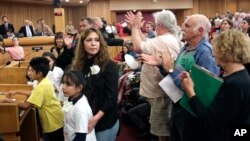 Nora Sandigo Otero and several children under her legal guardianship receive a standing ovation upon their arrival at a Miami-Dade County immigration hearing, Feb. 17, 2017, in downtown Miami. Sandigo Otero is asking Miami-Dade commissioners to reverse Mayor Carlos Gimenez's position on immigration that requires local police to work with federal officers to enforce immigration law.