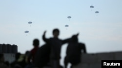 Ljudi gledaju kako američka vojska izbacuje prvu rundu pomoći iznad Gaze, 2. marta 2024.