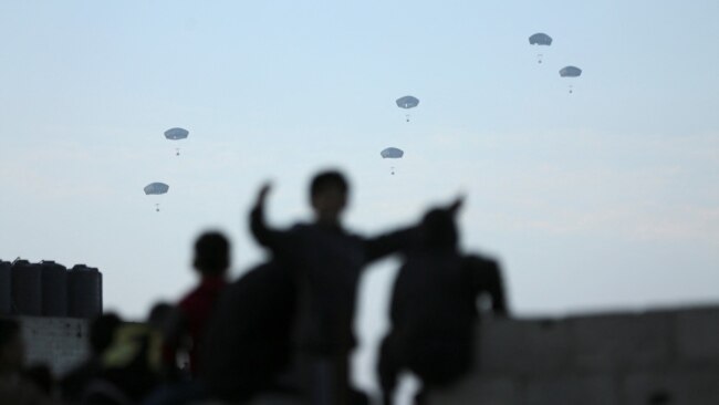 People watch as the U.S. military carries out its first aid drop over Gaza, in Gaza City on March 2, 2024.