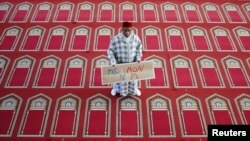 FILE - Muslim Khaloar Abdarahim holds a placard which reads "Not in my name" as he poses inside the Arrahma Mosque after Friday prayers in Nantes, western France, Sept. 26, 2014 after a gathering to pay tribute to French mountain guide Herve Gourdel who was beheaded by an Algerian Islamist group.