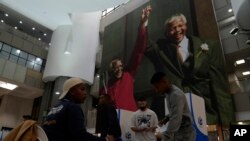 FILE— A man casts his vote beneath an image of former president Nelson Mandela and the former Anglican Archbishop Desmond Tutu, at a polling station in Cape Town, South Africa, May 29, 2024.