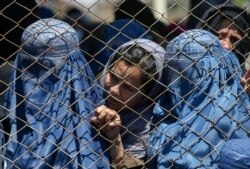 FILE - Afghan women wait to receive food aid in Kabul, Afghanistan, April 21, 2020. Their rights are expected to be dramatically curtailed with the return of the Taliban regime.