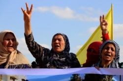 Kurdish women flash victory signs and shout slogans as they protest against possible Turkish military operation on their areas, at the Syrian-Turkish border, in Ras al-Ayn, Syria, Oct. 7, 2019.