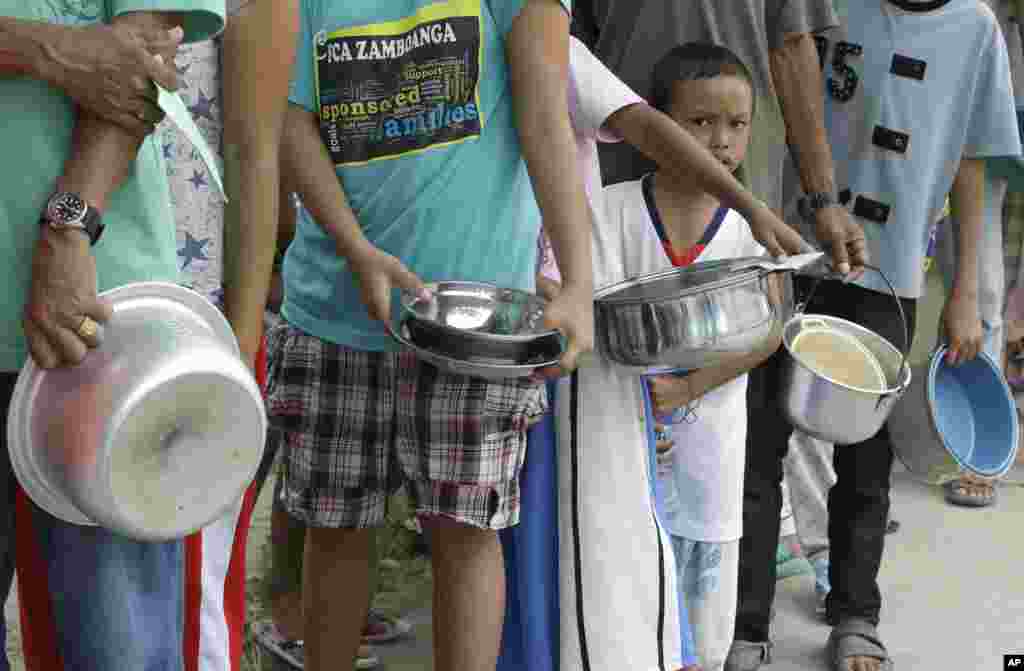 Parap pengungsi berbaris untuk mendapatkan makanan seiring berlanjutnya pertempuran antara pemerintah dan Muslim di Zamboanga, Filipina (19/9). (AP/Bullit Marquez)