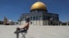 A masked Palestinian demonstrator holds a stone during clashes with Israeli security forces in front of the Dome of the Rock Mosque at the Al Aqsa Mosque compound in Jerusalem's Old City.