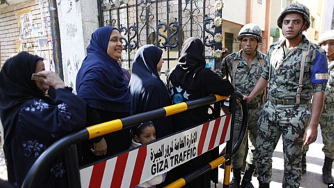 Egyptian women stand in line waiting to cast their votes at the entrance of an election center in Cairo, Egypt, December 15, 2011.