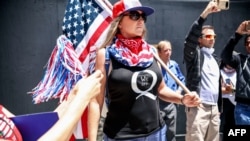 FILE - Conspiracy theorist QAnon demonstrators protest against coronavirus restrictions, in San Diego, California, May 01, 2020.