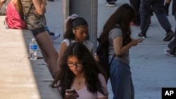 Students use their cellphones as they leave for the day the Ramon C. Cortines School of Visual and Performing Arts High School in downtown Los Angeles, Aug. 13, 2024.