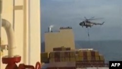 This image grab taken from a UGC video posted on social media on April 13, 2023, shows Iran's Revolutionary Guards rappelling down onto a container ship named, MSC Aries, near the Strait of Hormuz.