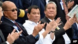 Philippine President Rodrigo Duterte, center, accompanied by Transportation Secretary Arthur Tugade, right, and Defense Secretary Delfin Lorenzana, left, clap their hands at the end of Japan's coast guard drills in Yokohama, Oct. 27, 2016.