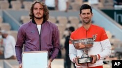 Serbia's Novak Djokovic, right, and Stefanos Tsitsipas of Greece pose with their trophies after their final match of the French Open tennis tournament at Roland Garros stadium in Paris, June 13, 2021.