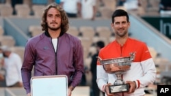 Serbia's Novak Djokovic, right, and Stefanos Tsitsipas of Greece pose with their trophies after their final match of the French Open tennis tournament at Roland Garros stadium in Paris, June 13, 2021.