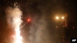 An Indian woman lights firecrackers on the street during the New Year celebration in Mumbai, India, Sunday, Jan. 1, 2017.