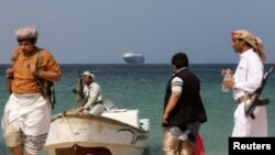 FILE PHOTO: Armed men stand on the beach as the Galaxy Leader commercial ship, seized by Yemen's Houthis last month, is anchored off the coast of al-Salif