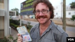 Graham Hughes brandishing his latest visa outside South Sudan's Ministry of Roads in Juba. The 33-year-old broke a world record when he reached South Sudan, the last on his list of 201 sovereign states to visit without flying.