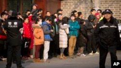 FILE - Chinese policemen watch as depositors from Ezubao gather outside the State Bureau for Letters and Calls Reception Division office in Beijing, Jan. 1, 2016. China's policy ministry says it investigated 380 online lenders following an avalanche of scandals.