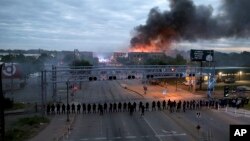 Law enforcement officers amassed along Lake Street near Hiawatha Ave. as fires burned after a night of unrest and protests in the death of George Floyd early May 29, 2020 in Minneapolis. 