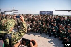 Personel militer dari Indonesia, Jepang, Singapura, Thailand, Inggris, dan Amerika Serikat foto bersama di Pusat Penerbangan Angkatan Laut Indonesia di Sidoarjo, Jawa Timur, 26 Agustus 2024. (JUNI KRISWANTO / AFP)