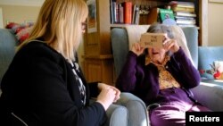 FILE - Daphne Padfield, 93, tries out a specialist virtual reality headset at the Langham Court Dementia Home in Hindhead, Britain, Feb. 6, 2018.