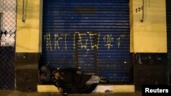 A homeless woman sleeps on a street on Christmas Eve in Sao Paulo, Brazil, Dec. 24, 2014. 