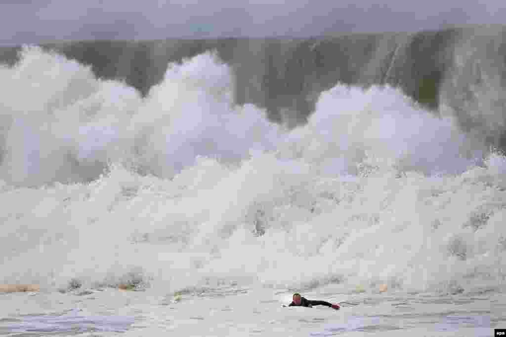 A surfer paddles back to shore when a huge wave crashes behind him at Narrabeen beach in Sydney&#39;s Northern Beaches, New South Wales, Australia.