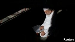 FILE - Abdul Barek Hajji, 70, a Bengali Muslim, reads the Koran while waiting for the Maghrib sunset prayer during Ramadan at the Abu Bakr Mosque, in Flushing, New York, May 31, 2017.