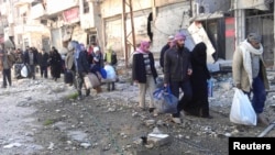 Thường dân mang theo đồ đạc để di tản khỏi thành phố Homs, 7/2/2014