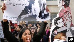 An Egyptian protester chants anti interior ministry slogans as she holds a poster of Shaimaa el-Sabagh, an activist who was shot dead at a small peaceful protest last Saturday, with Arabic that reads, " how many martyrs remaining for victory," during a wo