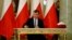 FILE - Zbigniew Ziobro signs documents after being designated as Minister of Justice, at the Presidential Palace in Warsaw, Poland, Nov. 15, 2019.
