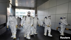 Workers from a disinfection service company sanitize a branch of the Shincheonji Church of Jesus the Temple of the Tabernacle of the Testimony, where a woman known as "Patient 31" attended a service in Daegu, South Korea, Feb. 19, 2020. 