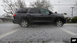 A car sends hail stones flying as it drives through a sudden hail storm that passed through the area Feb. 26, 2018, in Sacramento, Calif.