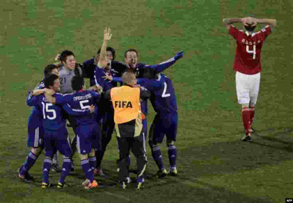 Denmark's Daniel Agger, right, walks off the pitch as Japanese players celebrate following the World Cup group E soccer match between Denmark and Japan at Royal Bafokeng Stadium in Rustenburg, South Africa, on Thursday, June 24, 2010. The match ended 3-1 