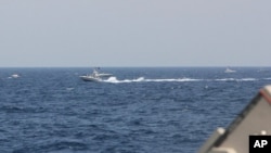 In this image provided by the U.S. Navy, an Iranian Islamic Revolutionary Guard Corps Navy fast in-shore attack craft is shown near U.S. naval vessels transiting the Strait of Hormuz, May 10, 2021. 